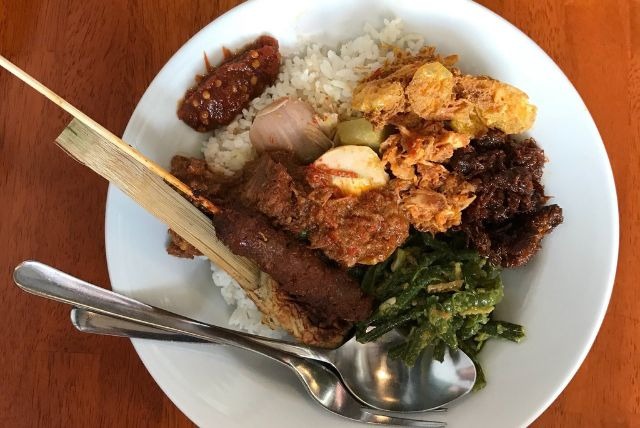 Sepiring Nasi Campur Bali Warung Wardani berisi sate lilit, ayam suwir, telur pindang, tempe dan kentang crispy, udang, dan sayuran lengkap.